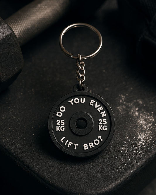 Black keychain with humorous text on a black surface with a dumbbell.