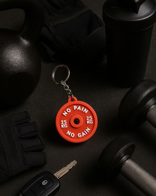 Red weightlifting keychain with 'No Pain, No Gain' text on a dark surface with fitness equipment.