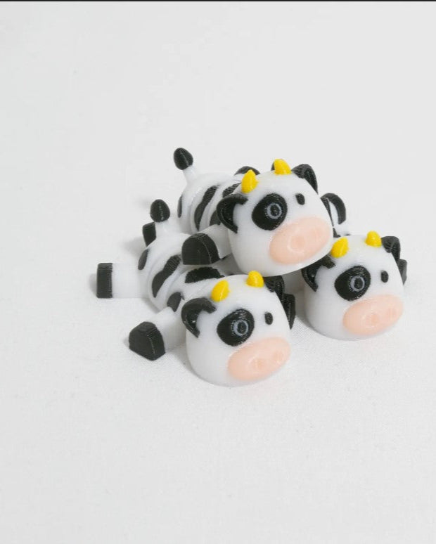 Three cow-shaped toys with black spots on a white background