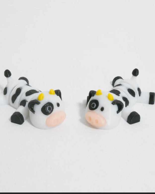 Two cow-shaped cake toppers on a white background