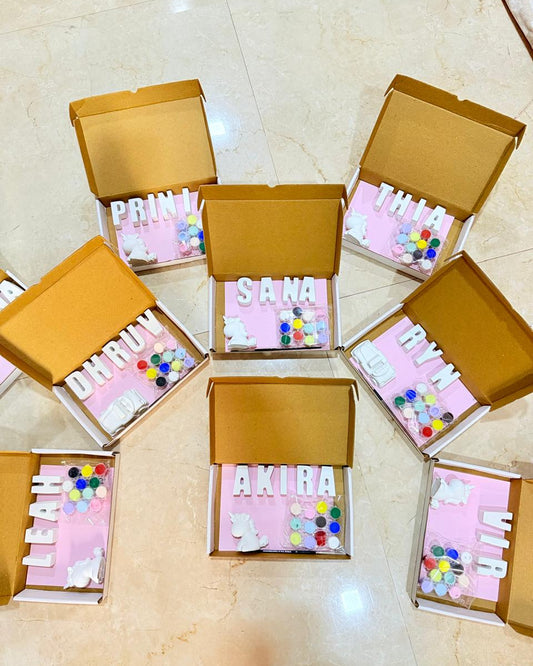 Open cardboard boxes with names printed on them, filled with colorful items, on a tiled floor.