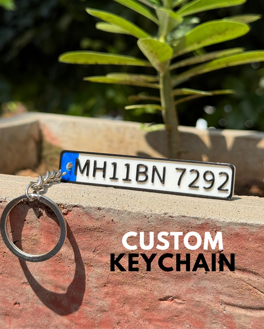 Custom keychain with license plate design on a wooden surface with greenery in the background