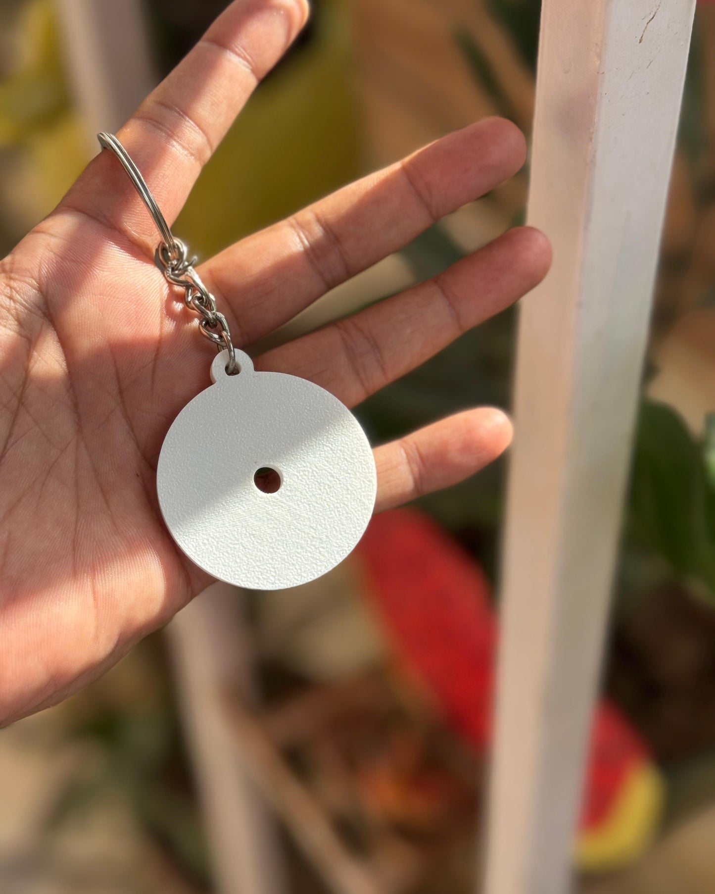 Hand holding a white circular keychain with a blurred background