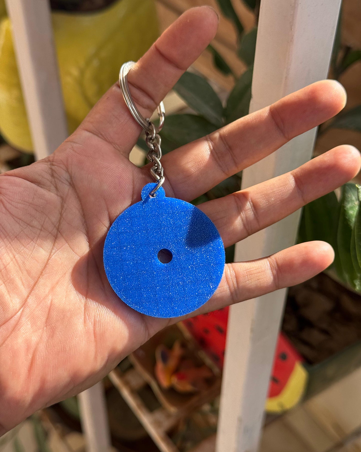Hand holding a blue keychain with a white background