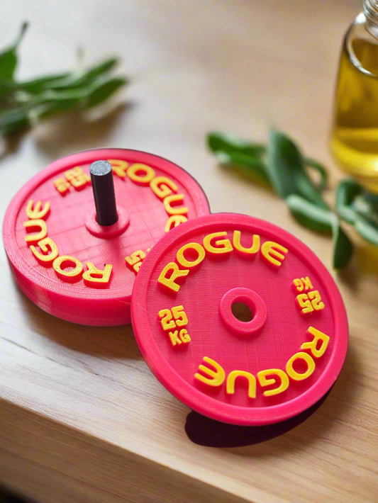 Two pink Rogue weight plates with yellow text on a blurred background