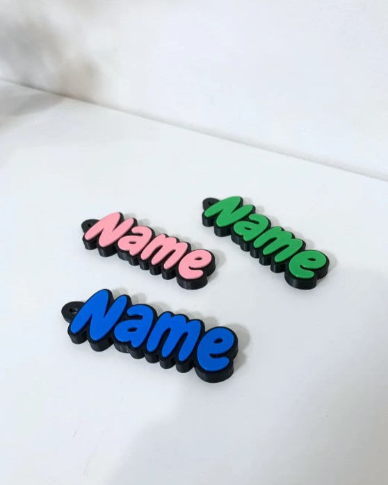Three colorful 'Name' stickers on a white surface