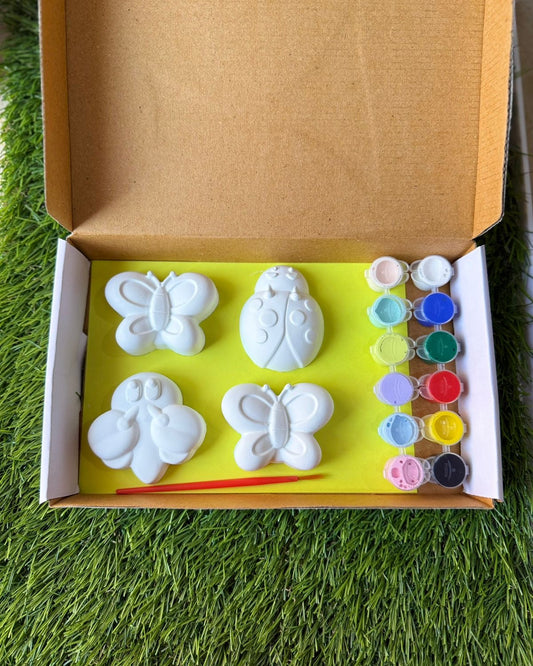 Box with butterfly-shaped molds and paint on a grassy background