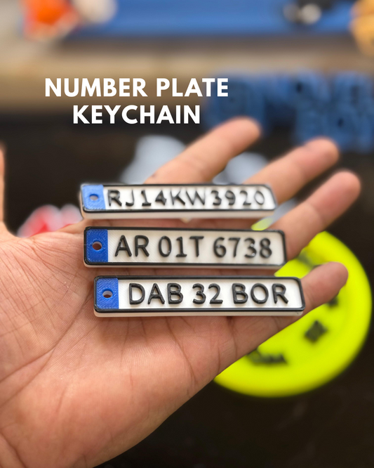 Hand holding three number plate keychains with blurred background