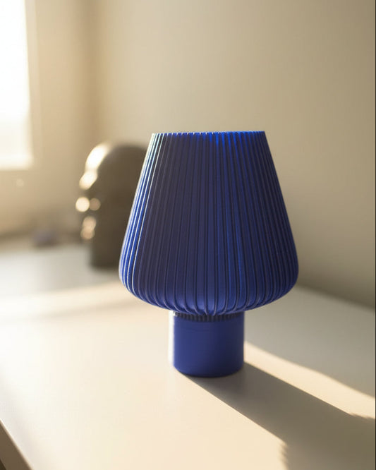 Blue pleated lampshade on a white surface with a blurred background