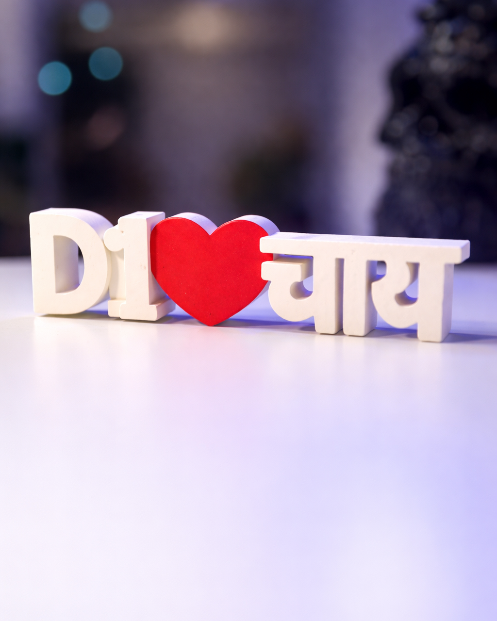 White letters spelling 'I love chai' with a red heart on a blurred background