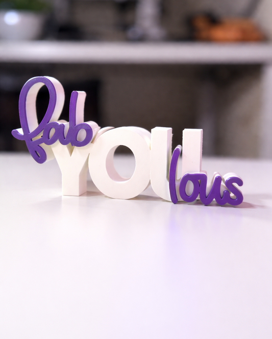 Decorative word sculpture spelling 'fab you Ious' on a white surface with a blurred background.