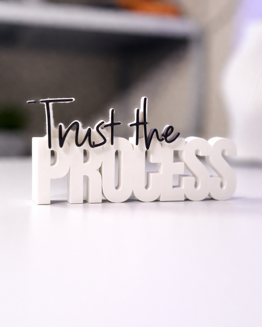 Decorative sign with 'Trust the Process' text on a blurred background