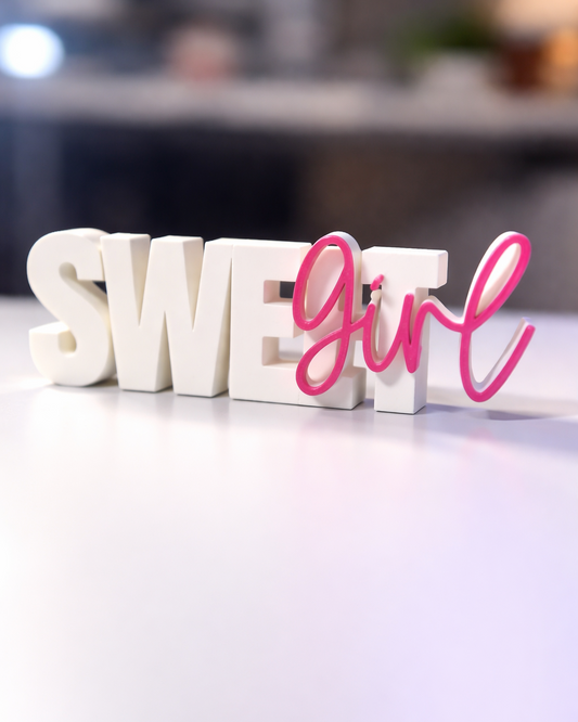 Decorative letters spelling 'SWEET GIRL' on a surface with a blurred background