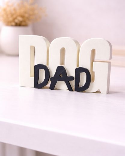 Decorative letters spelling 'DOG DAD' on a white surface with a blurred background