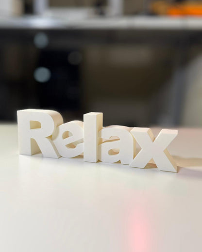 3D-printed 'Relax' word on a blurred background