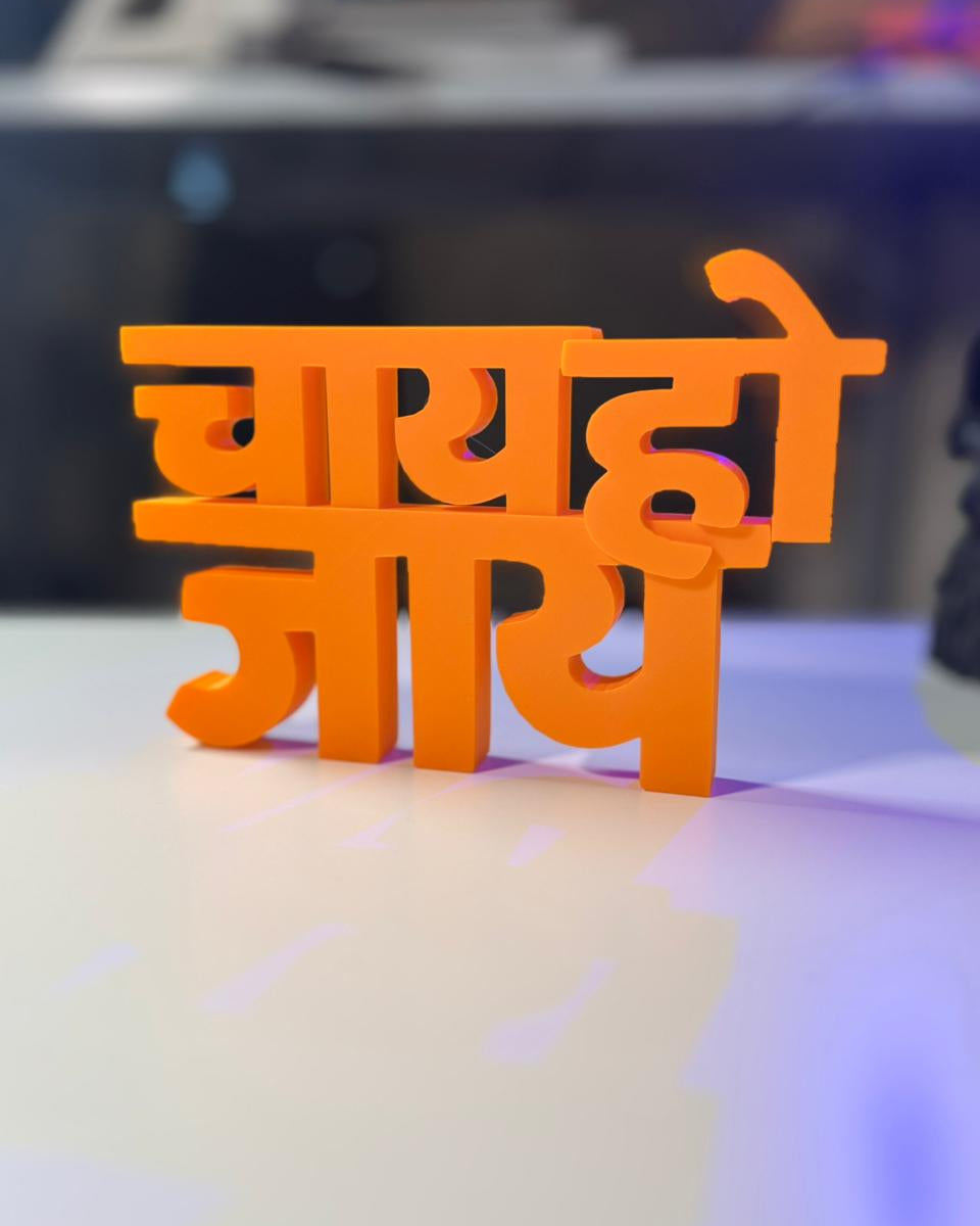 Orange 3D-printed text on a reflective surface with a blurred background