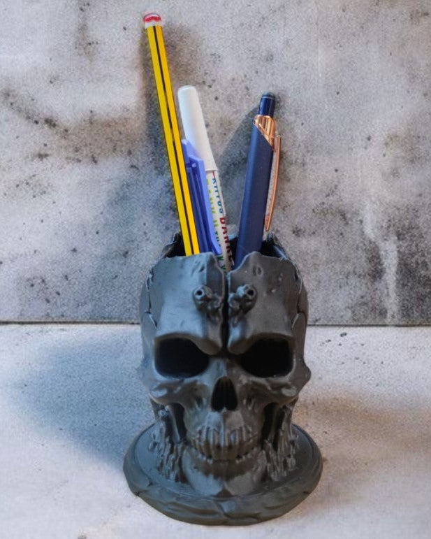 Skull-shaped pencil holder with pens on a concrete surface