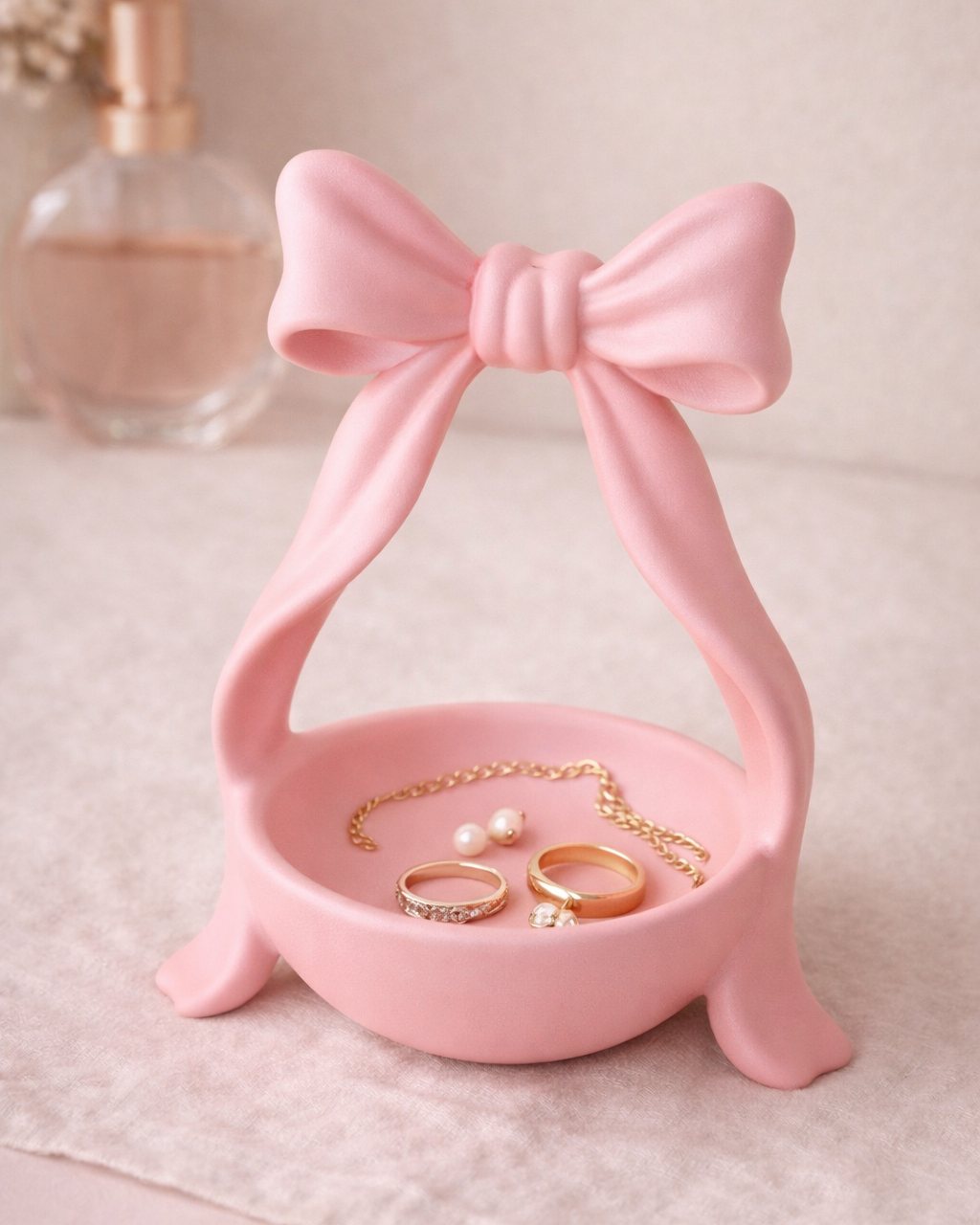 Pink jewelry stand with a bow design holding rings and a necklace on a light background.