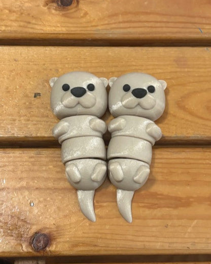 Two small gray otter figurines on a wooden surface