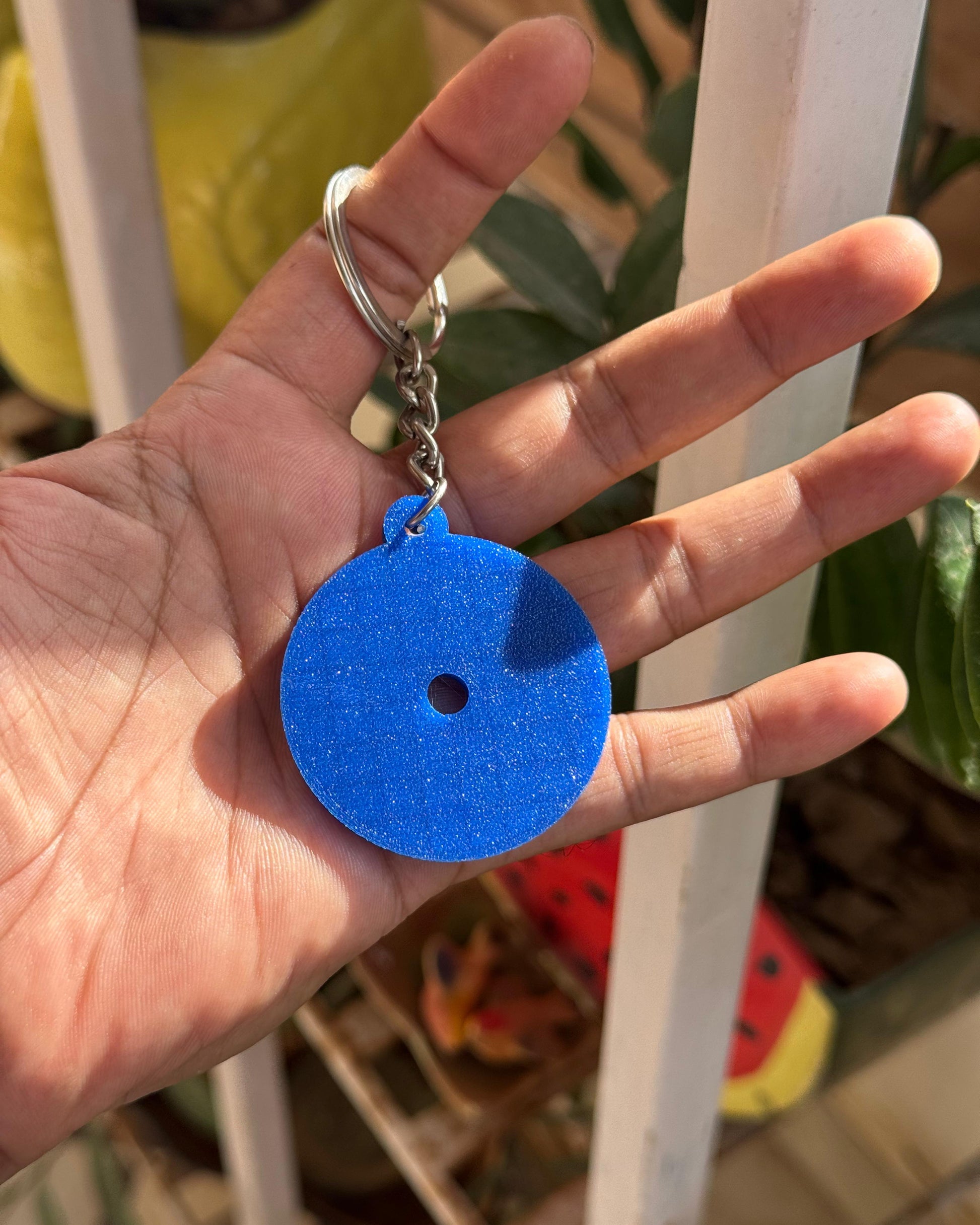 Hand holding a blue keychain with a white background