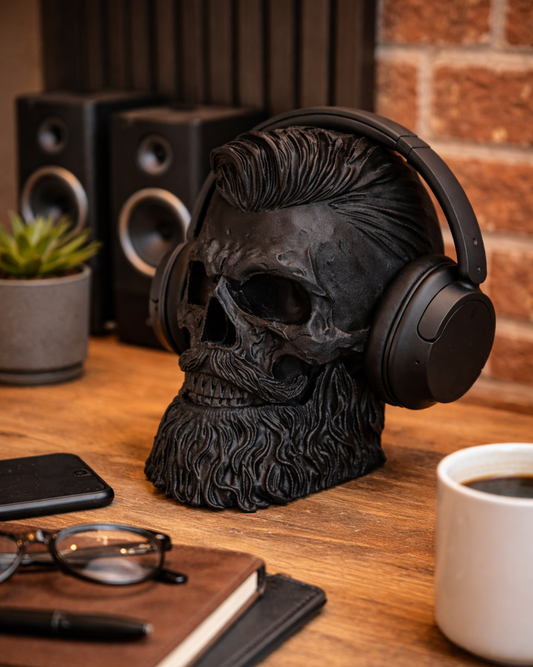Skull with mohawk wearing headphones on a desk with coffee and glasses