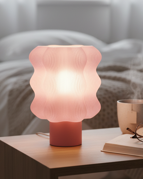 Pink textured table lamp on a bedside table with a cup, glasses, and book in a bedroom setting.