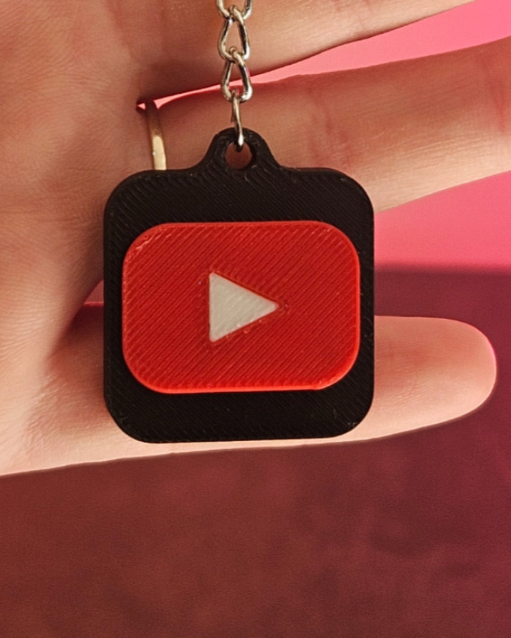 YouTube keychain with red play button logo on a pink background