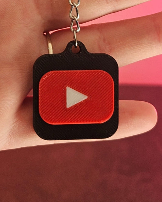 YouTube keychain with red play button logo on a pink background
