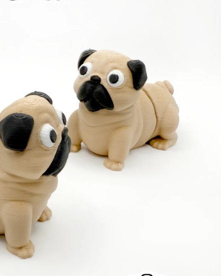 Two toy pugs with black faces on a white background
