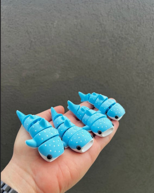 Hand holding blue dinosaur-shaped objects against a dark background