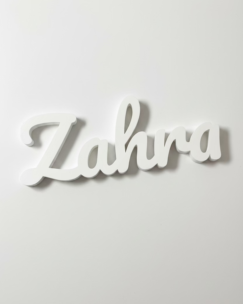 White nameplate with 'Zahra' on a reflective surface